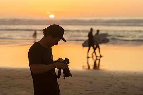 Fotograph schaut am Strand bei Sonnenuntergang auf Canon Kamera Display
