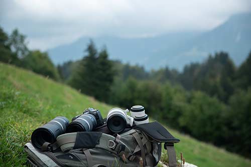 Canon Kameras und Objektive auf einem Rucksack auf einer Wiese am Berghang